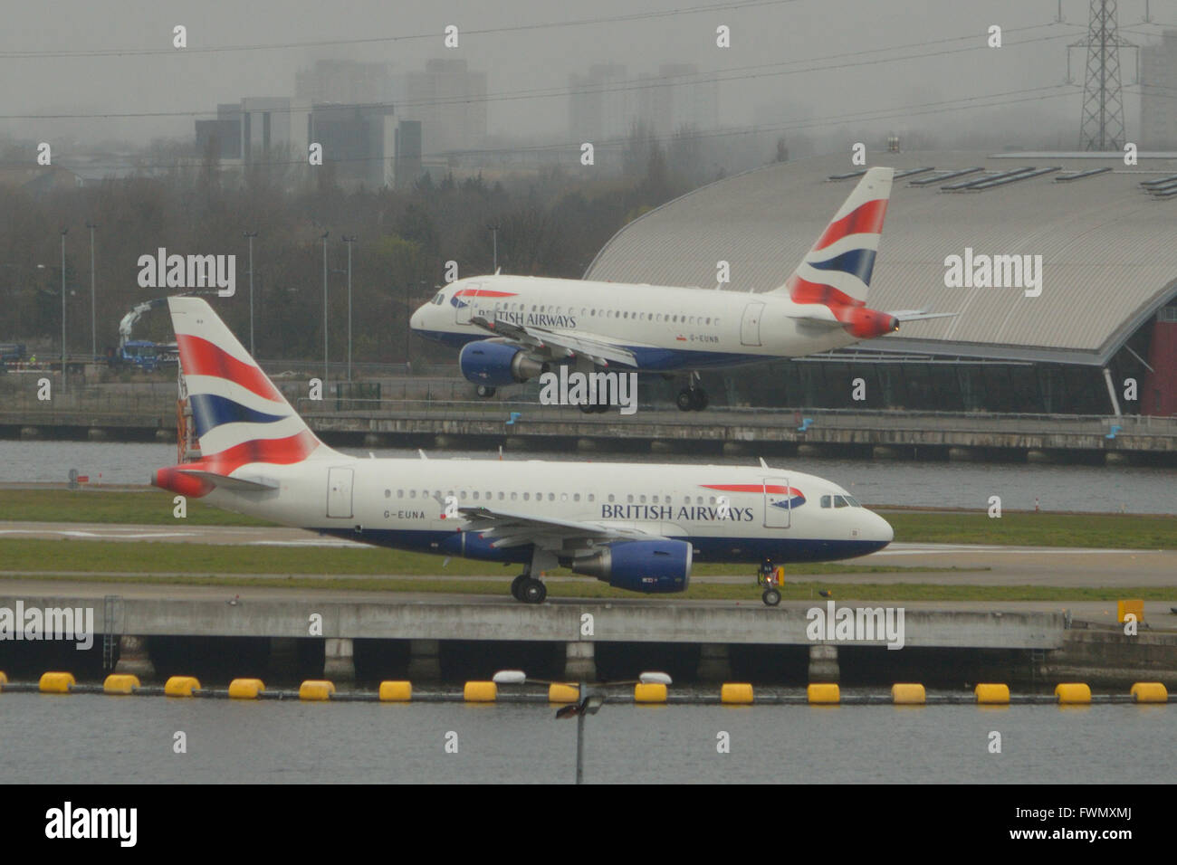 Die zwei British Airways A318 "Baby-Bus" jets am London City Airport - G-EUNA zu fahren, wie G-EUNB kommt Stockfoto