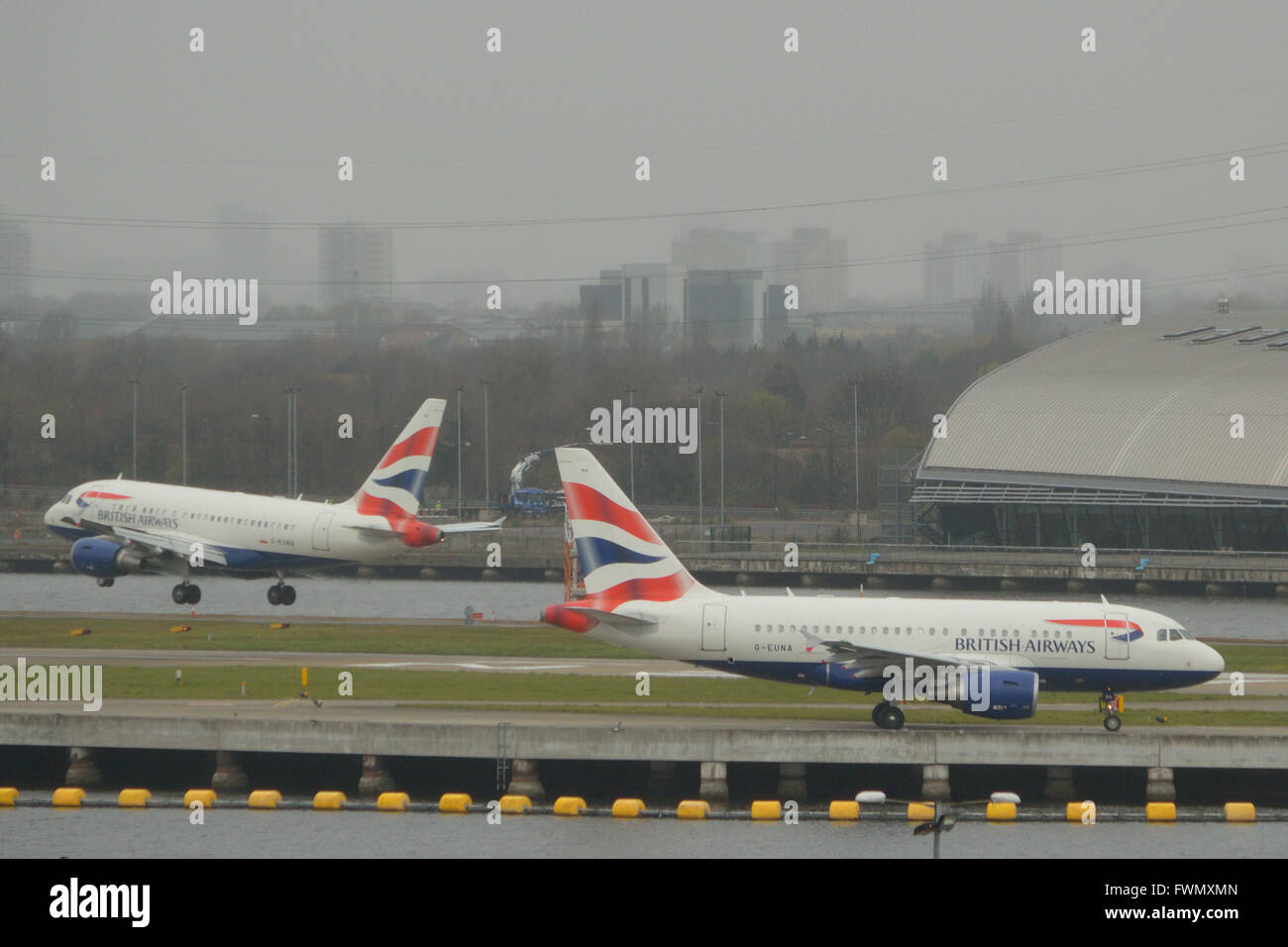 Die zwei British Airways A318 "Baby-Bus" jets am London City Airport - G-EUNA zu fahren, wie G-EUNB kommt Stockfoto