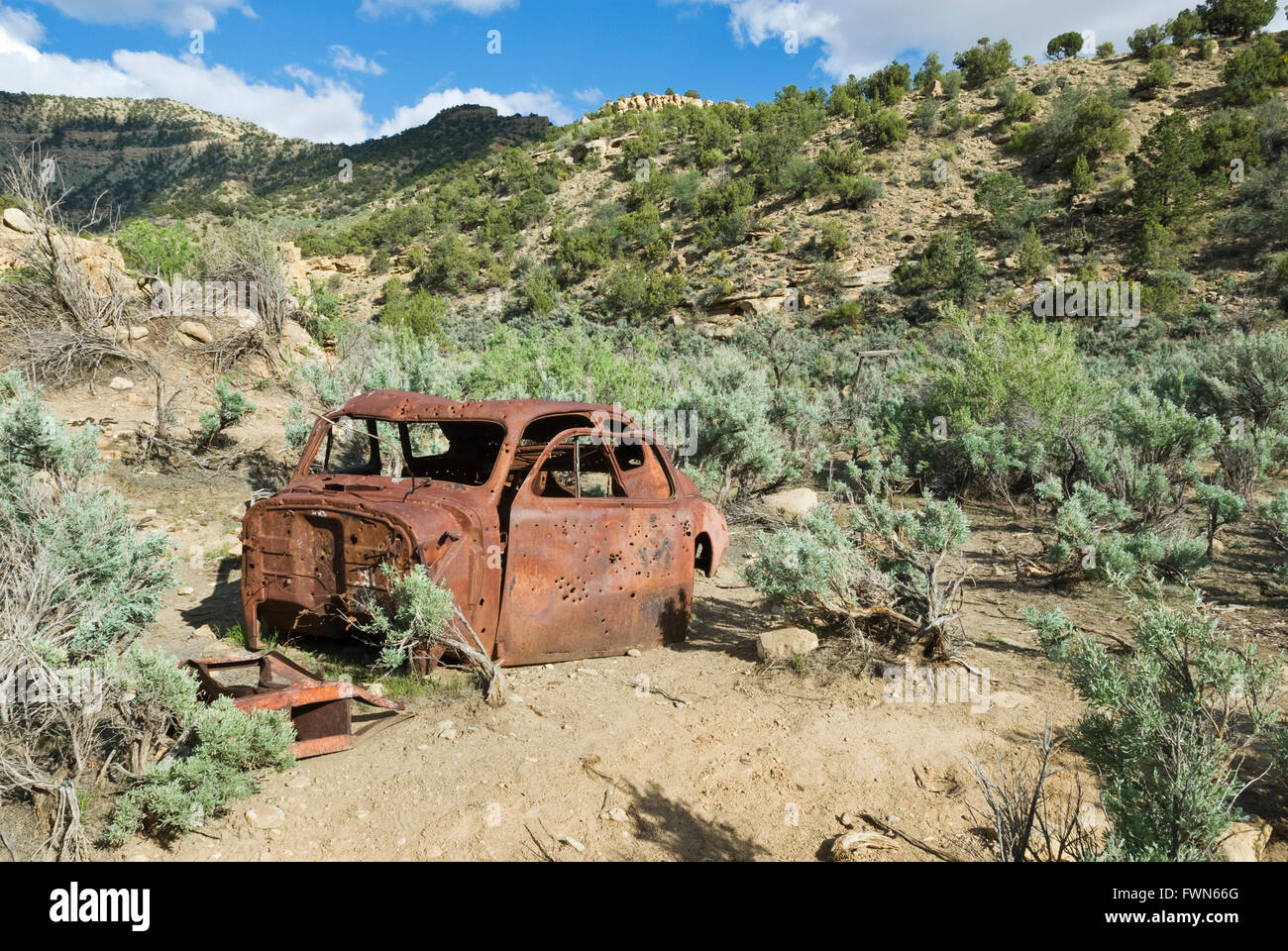 Ein rostiges Autowrack, gespickt mit Einschusslöchern liegt Rosten in der Nähe von Sego Geisterstadt, Utah, USA Stockfoto