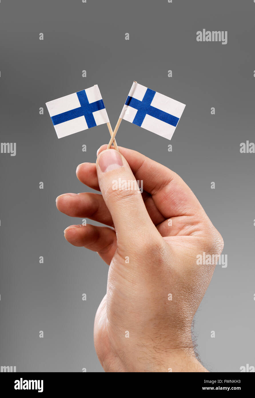 Mann, der zwei kleine Flaggen Finnlands in der Hand hält. Stockfoto