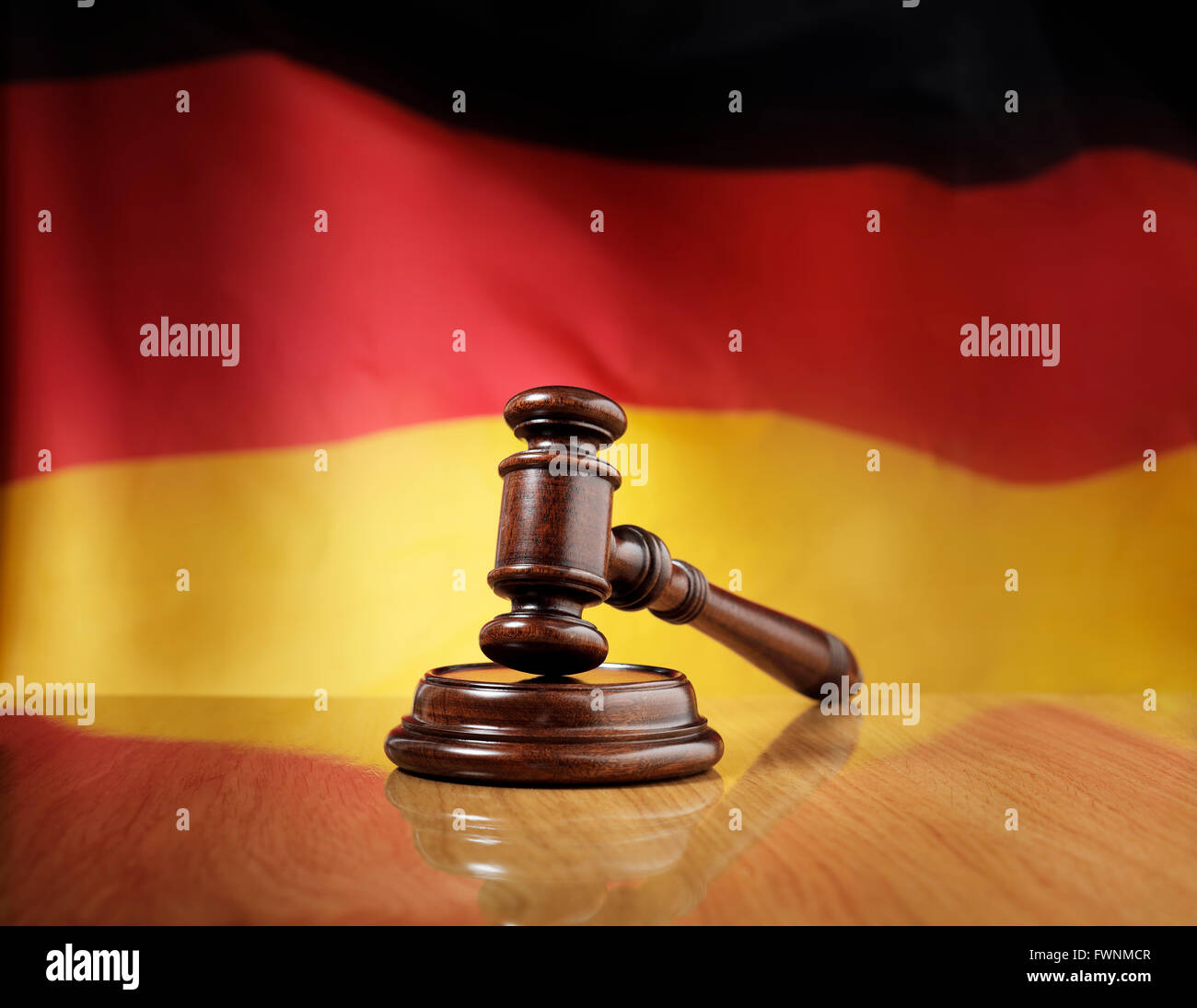 Mahagoni Holz Hammer auf glänzende Holztisch, Flagge von Deutschland im Hintergrund. Stockfoto