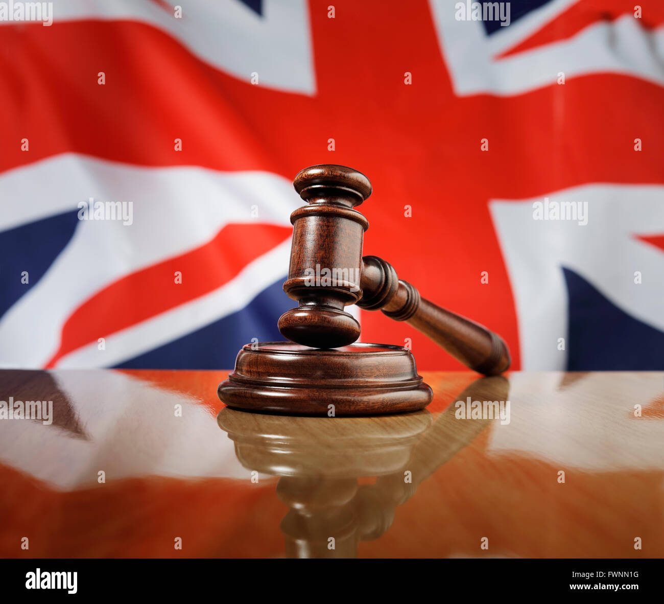 Mahagoni Holz Hammer auf glänzende Holztisch. Flagge des Vereinigten Königreichs im Hintergrund. Stockfoto