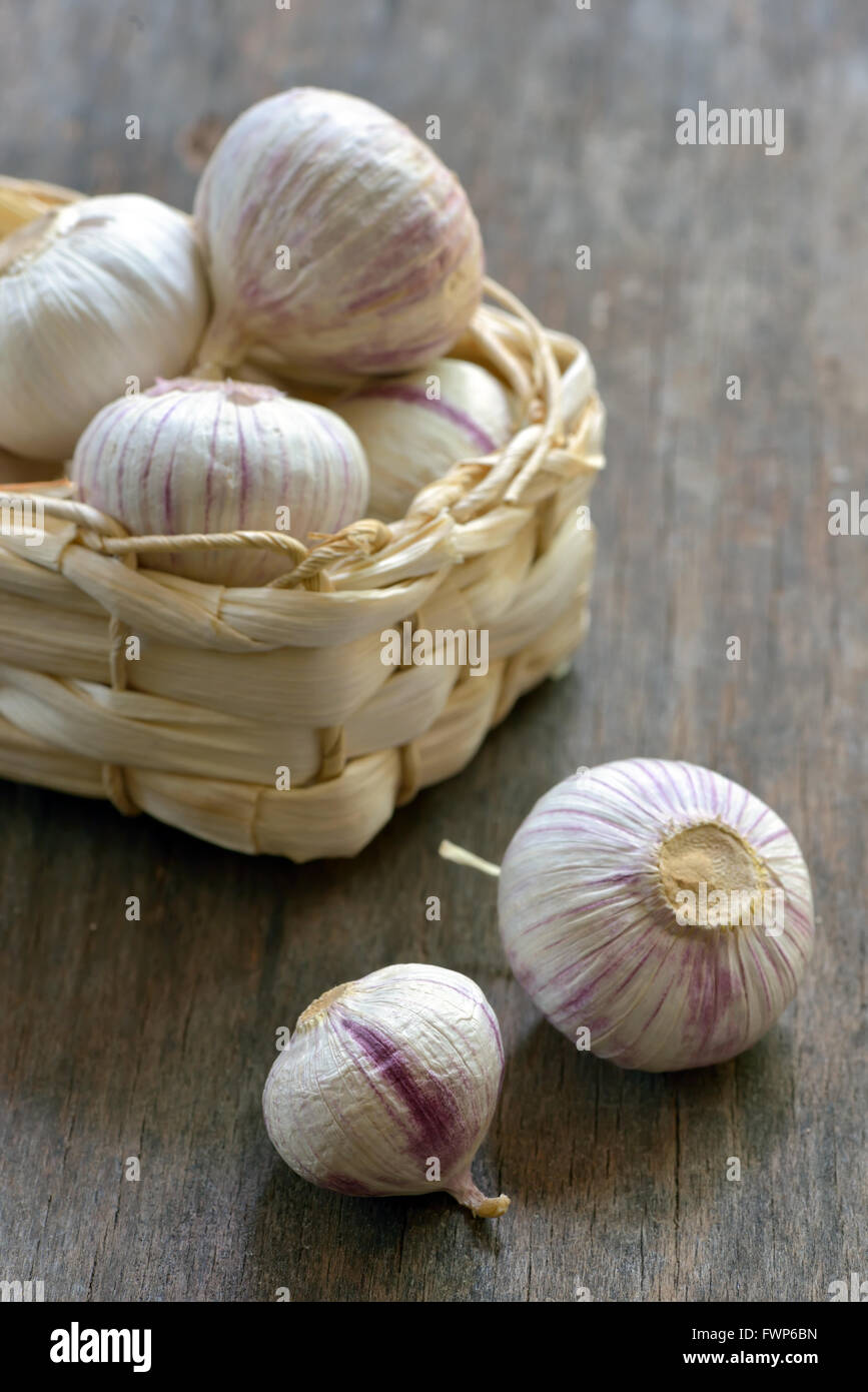 Knoblauch und kleinen Korb auf Holz Hintergrund Stockfoto