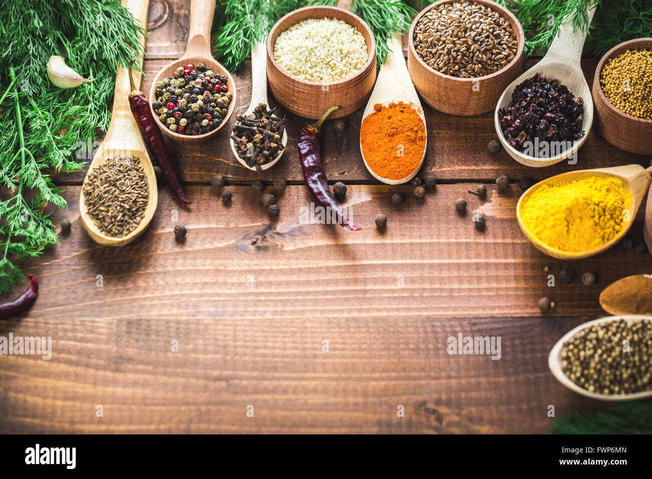 Schöne bunte Gewürze in hölzerne Löffel und Schüsseln auf einem alten hölzernen braun Tabelle. freier Platz für Ihren Text Stockfoto