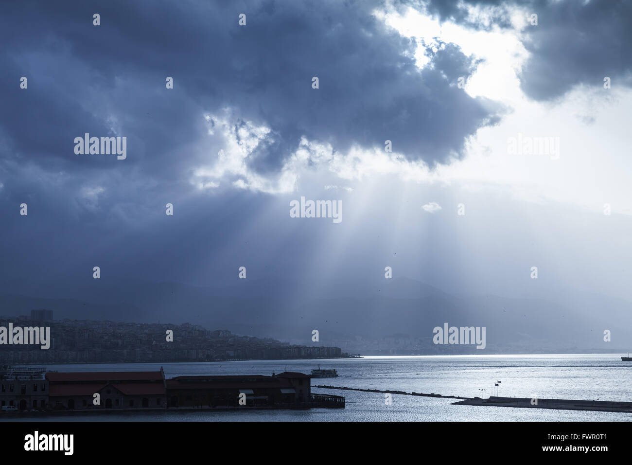 Dunkle dramatische Seelandschaft mit Wolken und Sonnenstrahlen über Meer. Blau getönten Foto-Filter-Effekt Stockfoto