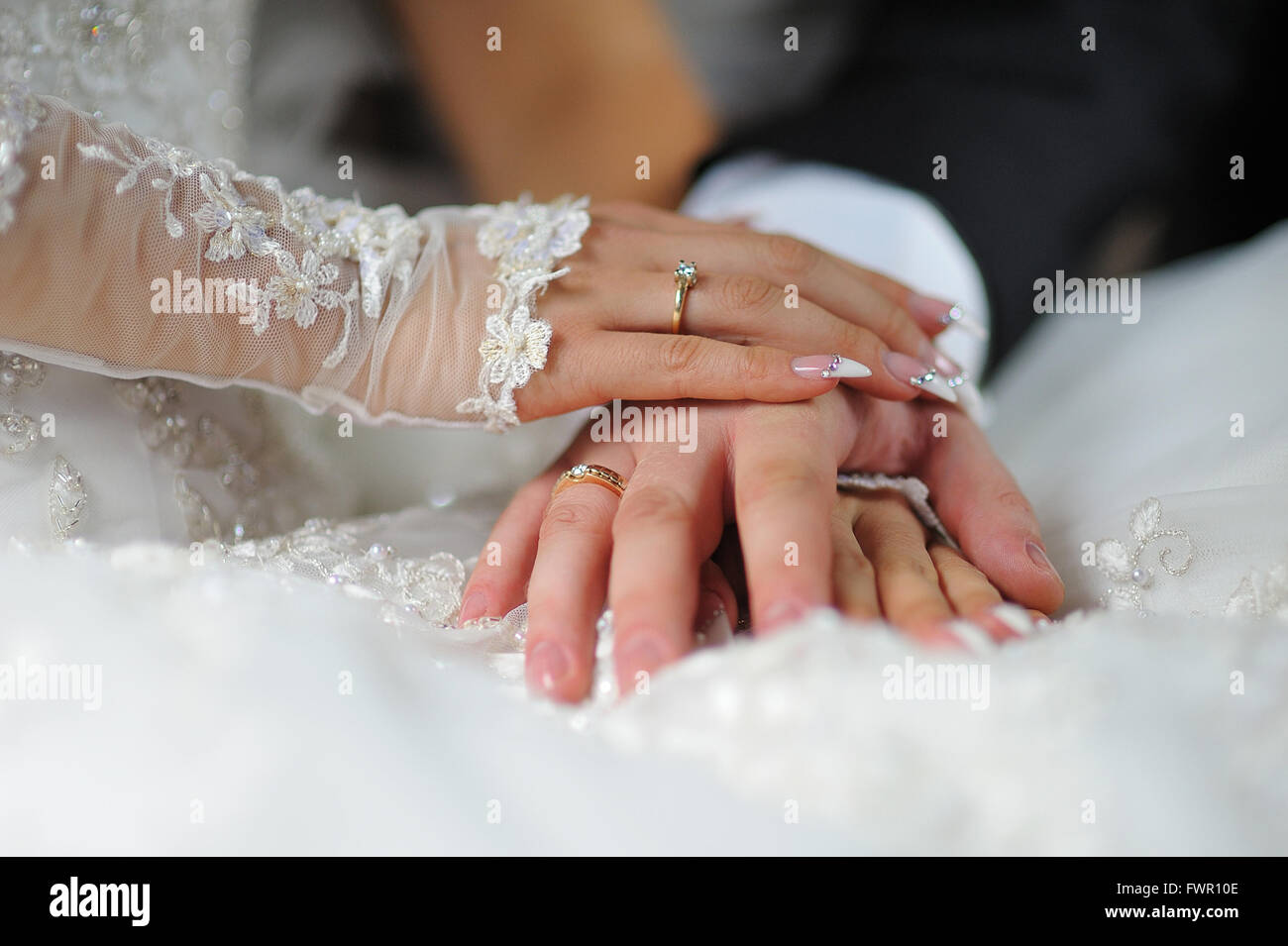 Hände der Braut und des Bräutigams mit Ringen auf dem Kleid Stockfoto