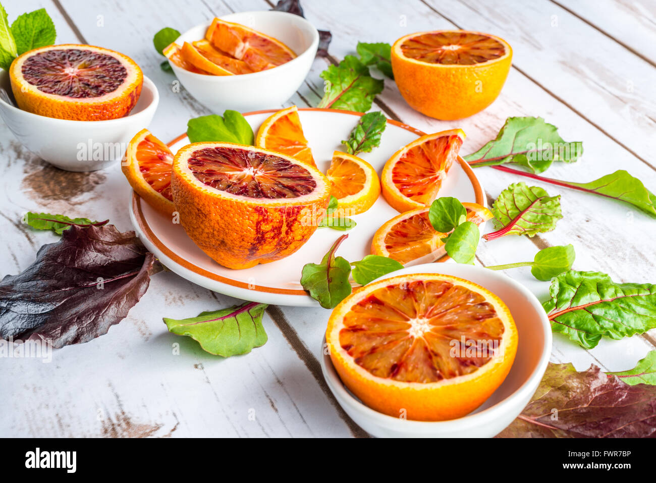 Blutorangen auf weißen Tellern mit grünem Salat Blätter Stockfoto