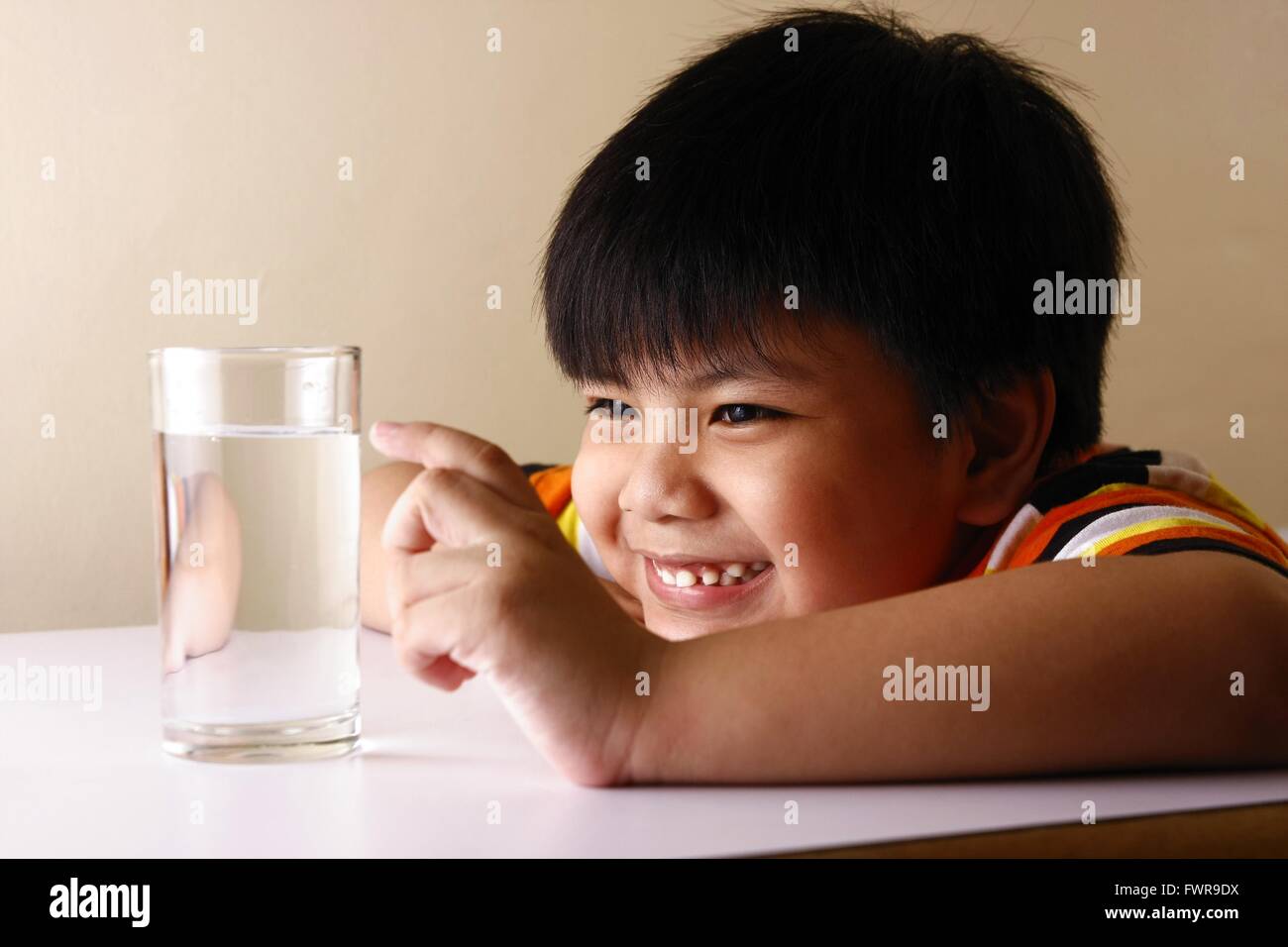 Kind ein Glas Wasser auf einem Holztisch zu berühren Stockfoto