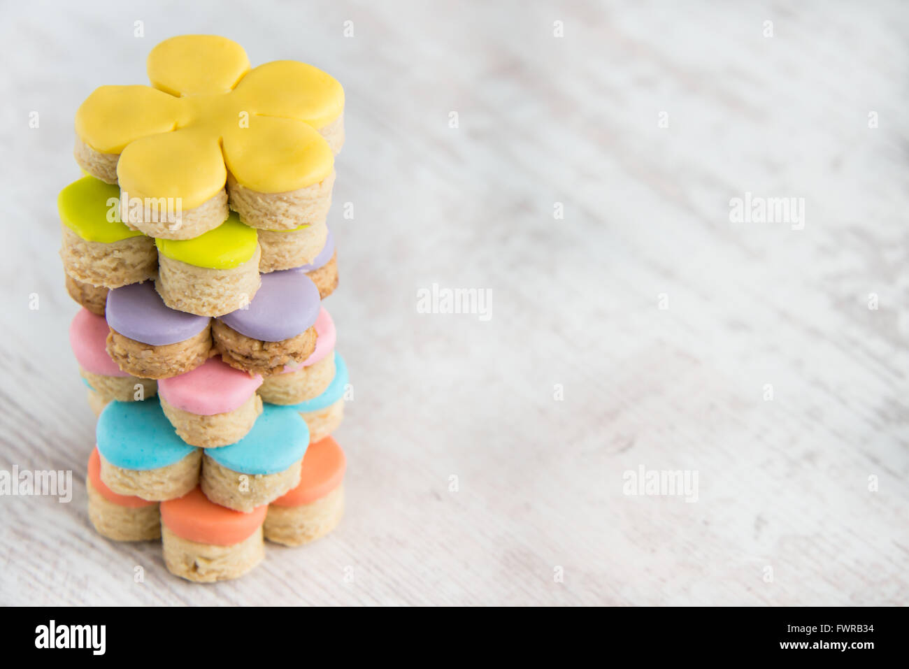 Nahaufnahme der bunten Blume Form selbstgemachten Fondant bedeckt Cookies auf einem weißen Hintergrund Holz Stockfoto