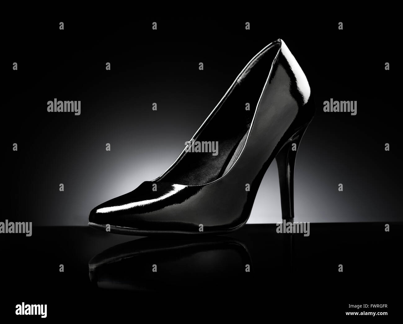 Schwarz glänzend Damen Pfennigabsatz Pumpen auf schwarzen reflektierenden Hintergrund. Stockfoto