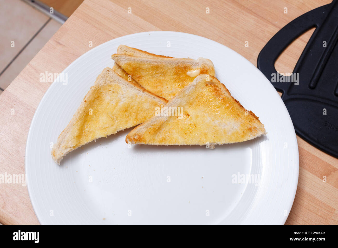 Drei Stücke von weißen Toast mit Butter auf einem weißen Teller Stockfoto