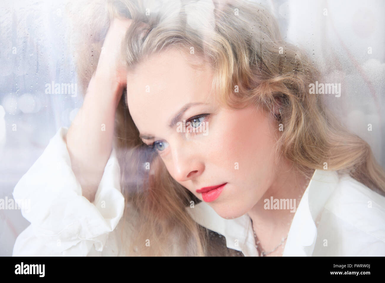 Porträt einer traurig schöne Frau am Fenster an einem regnerischen Tag Stockfoto