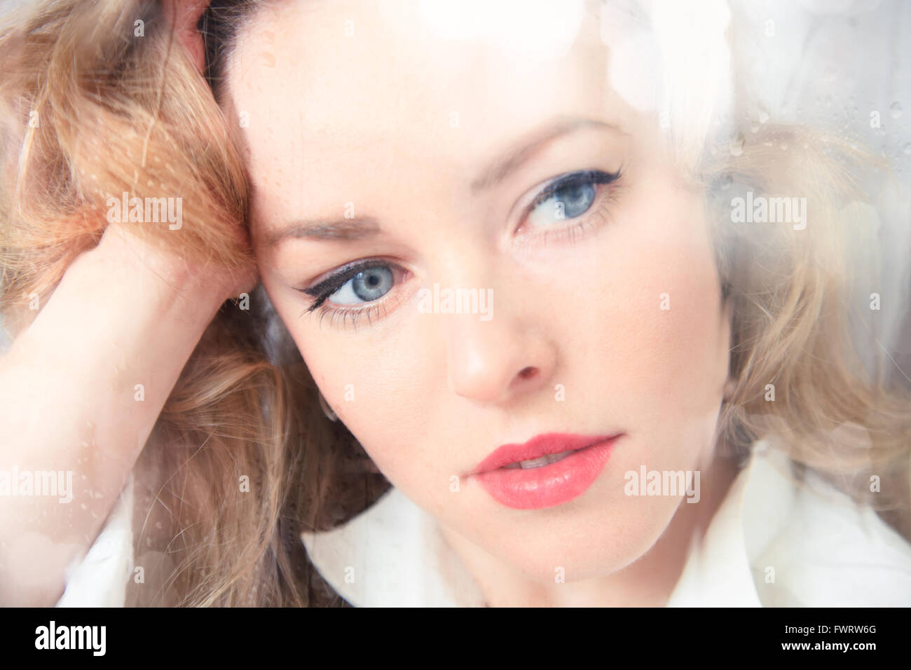 Close-up Portrait einer traurig schöne Frau neben dem Fenster an einem regnerischen Tag Stockfoto