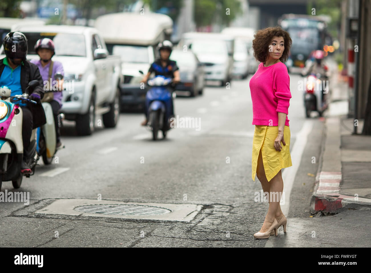 Junge asiatische Frau steht in der Nähe von einer geschäftigen Stadt-Autobahn. Stockfoto