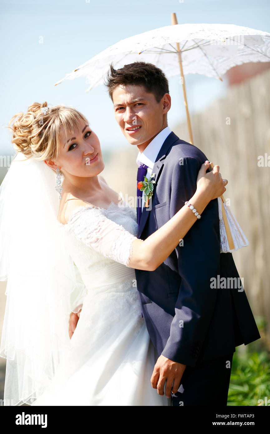 Braut und Bräutigam unter weißen Schirm auf sonnigen Tag Stockfoto