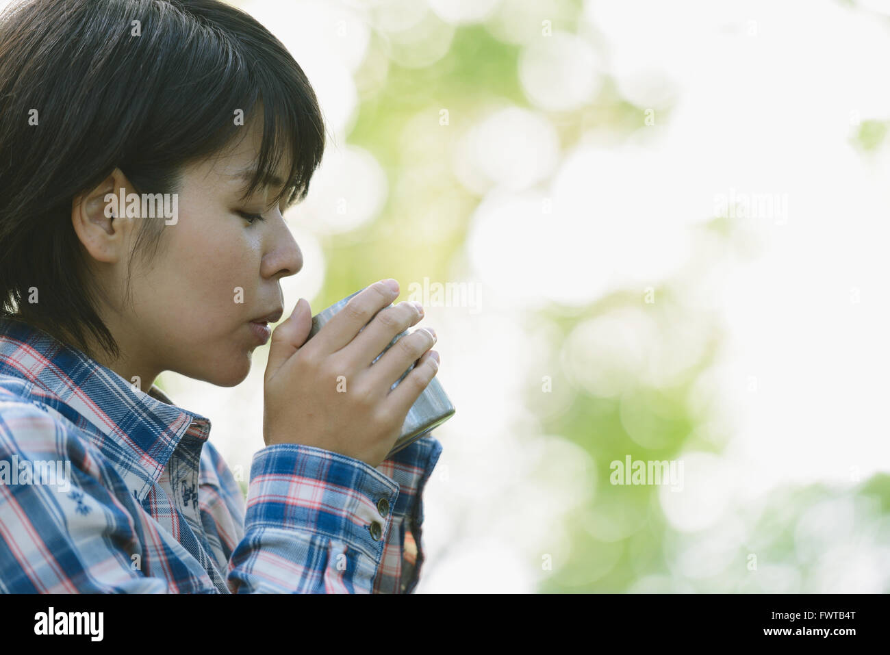 Junge Japanerin Kaffeetrinken auf einem Campingplatz Stockfoto