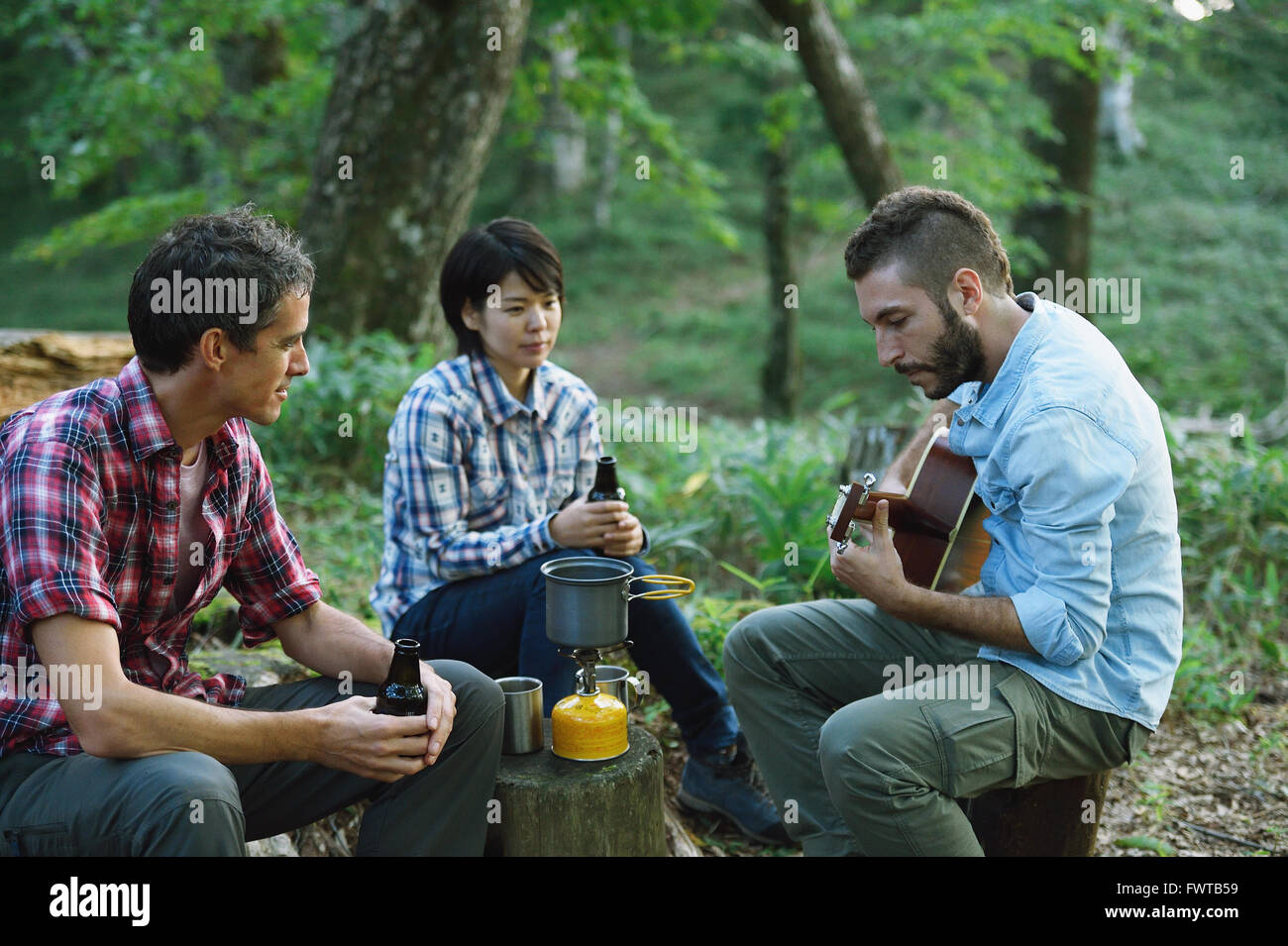 Multi-ethnischen Gruppe von Freunden, die Gitarre zu spielen, auf einem Campingplatz Stockfoto
