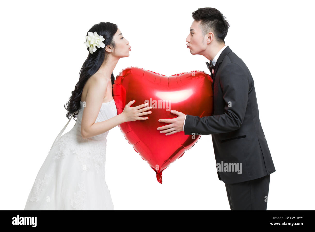 Glückliche Braut und Bräutigam halten einen herzförmigen Ballon Stockfoto