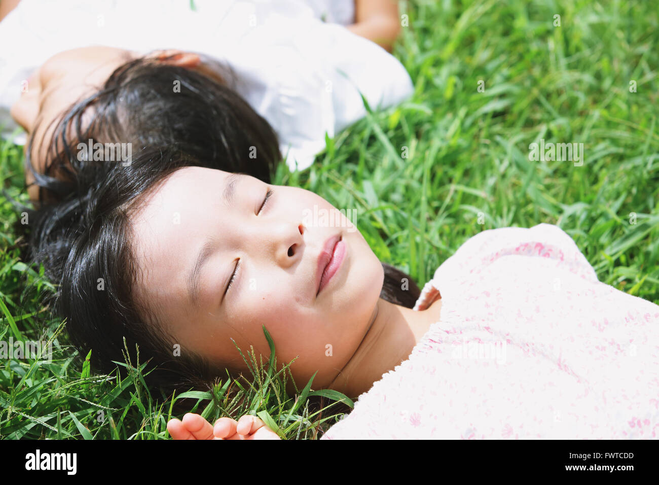 Japanische Kinder Verlegung auf Rasen in einem Stadtpark Stockfoto