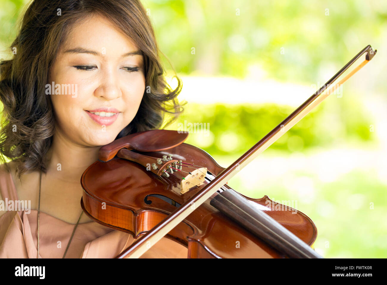 Junge Frau spielt Geige im Garten Stockfoto