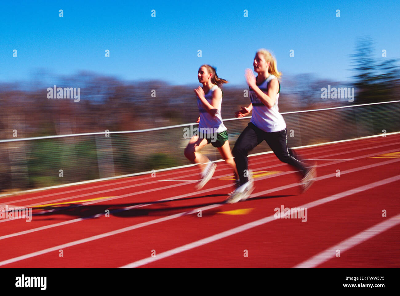 Pan Unschärfe Blick auf High School Mädchen Leichtathletik-Team läuft auf synthetische Oberfläche Outdoor-Strecke Stockfoto
