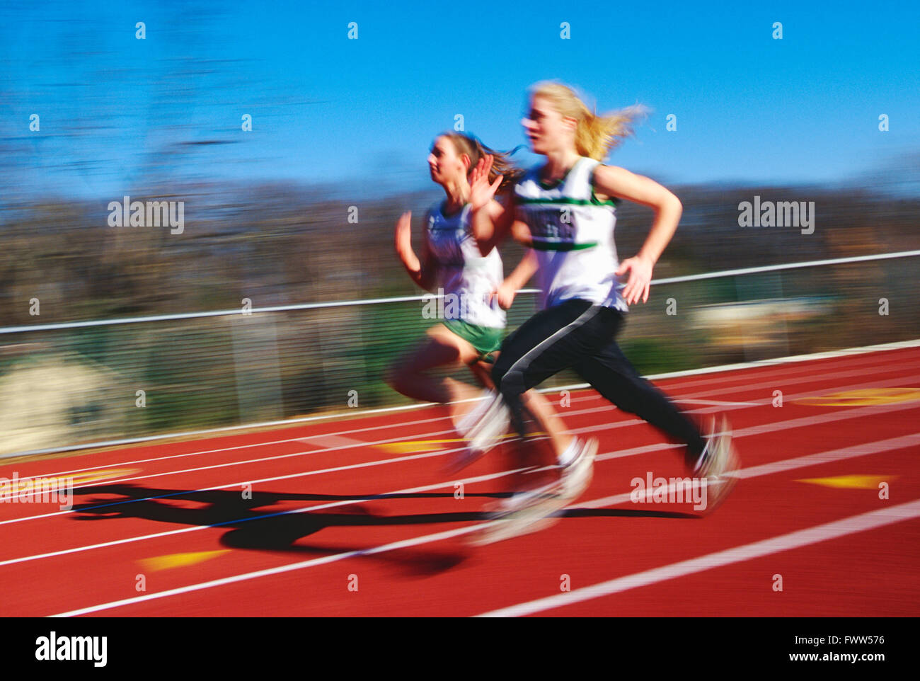 Pan Unschärfe Blick auf High School Mädchen Leichtathletik-Team läuft auf synthetische Oberfläche Outdoor-Strecke Stockfoto