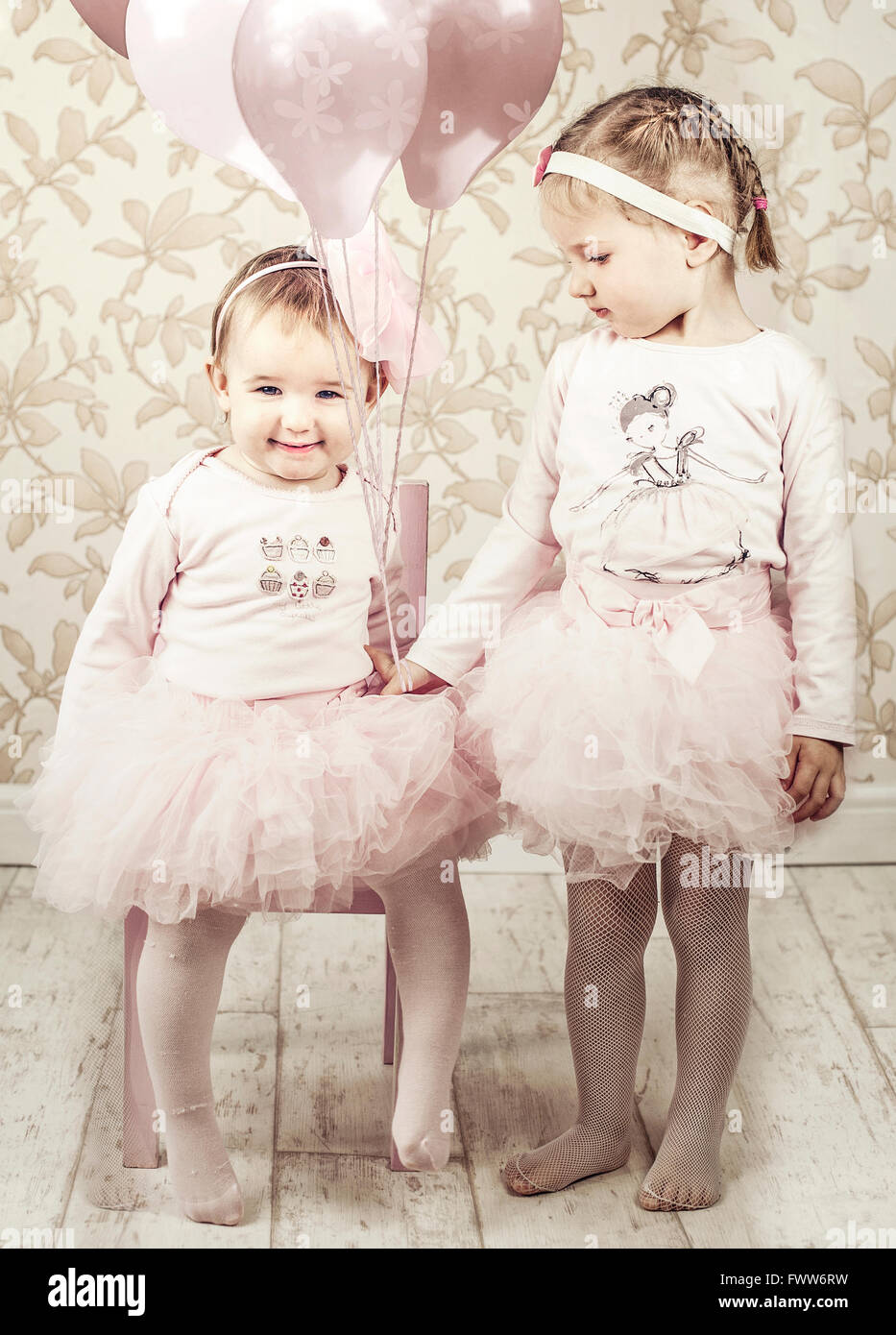 zwei kleine Mädchen Schwestern, in einem Raum mit Luftballons, Stockfoto