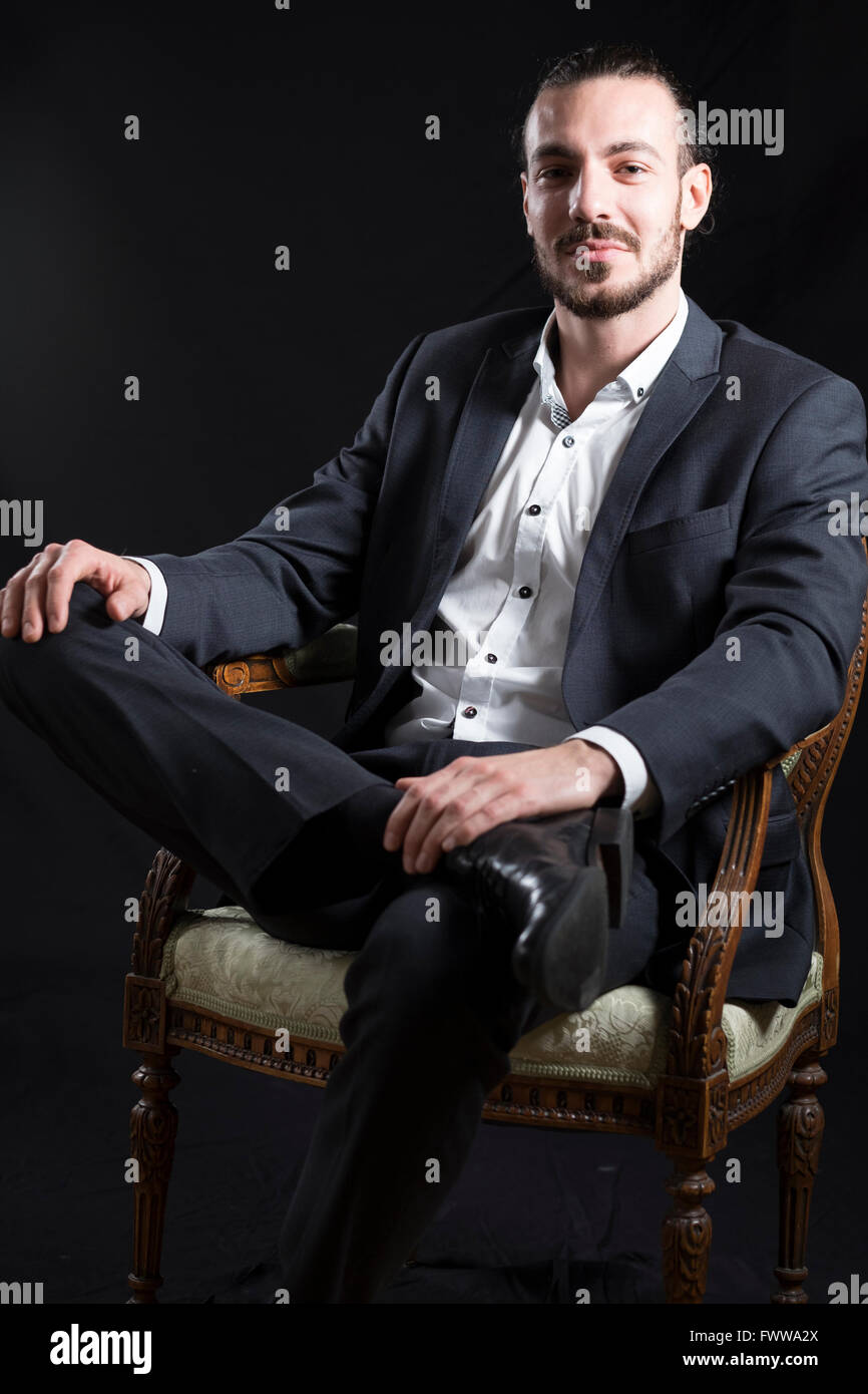 Junger Mann sitzen in einem alten Stuhl ein Bein Stockfoto Junger Mann sitzen in einem alten Stuhl ein Bein Stockfoto