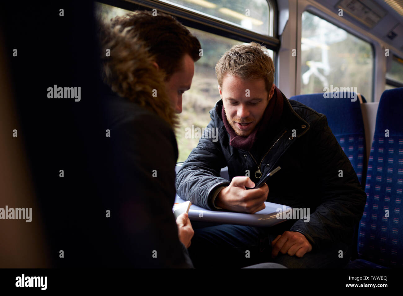 Zwei Männer sitzen im Zug Wagen Blick auf SMS Stockfoto