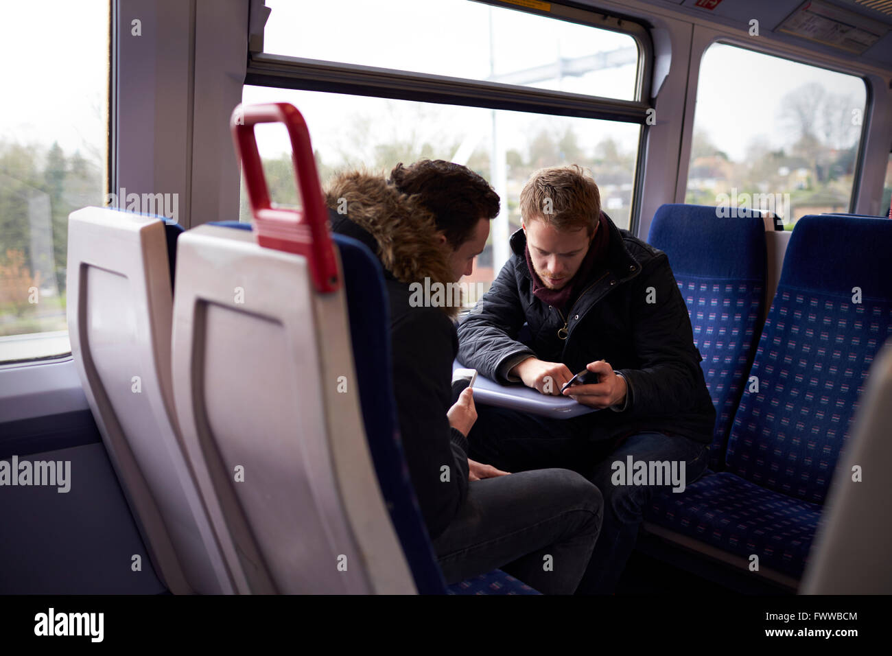 Zwei Männer sitzen im Zug Wagen Blick auf SMS Stockfoto