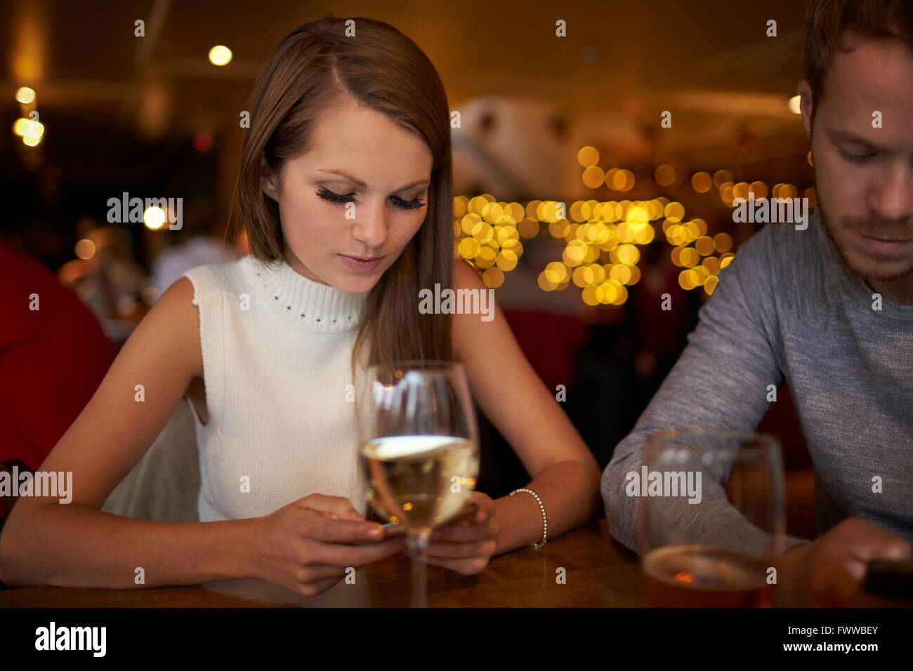 Junges Paar sitzt Bar SMS Stockfoto