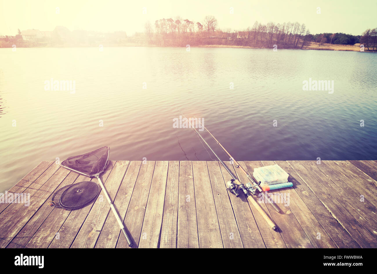 Vintage getönten Angelausrüstung auf einem hölzernen Pier bei Sonnenuntergang. Stockfoto