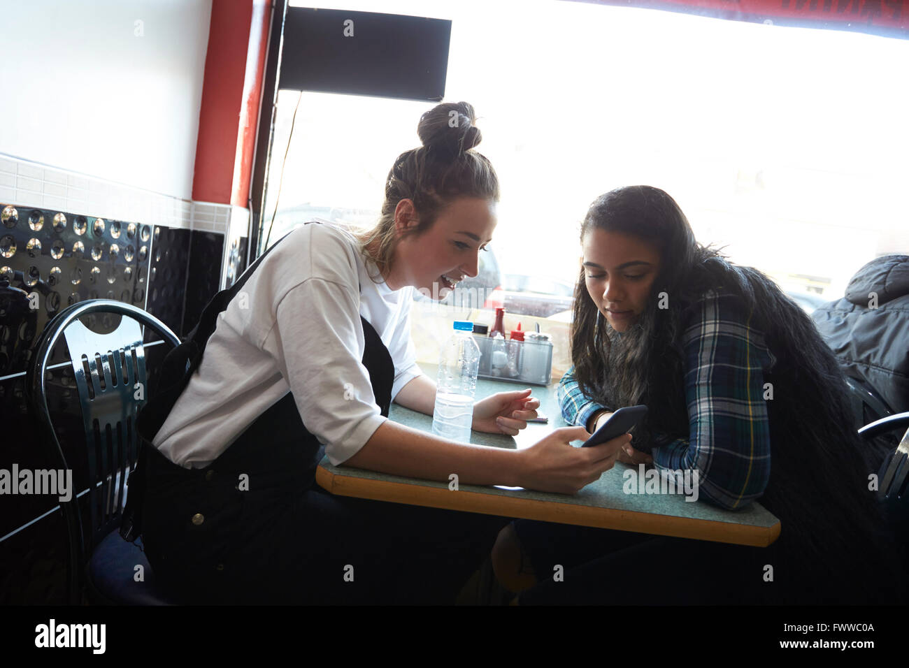 Zwei Studentinnen im Café überprüfen Sie Nachrichten auf dem Handy Stockfoto