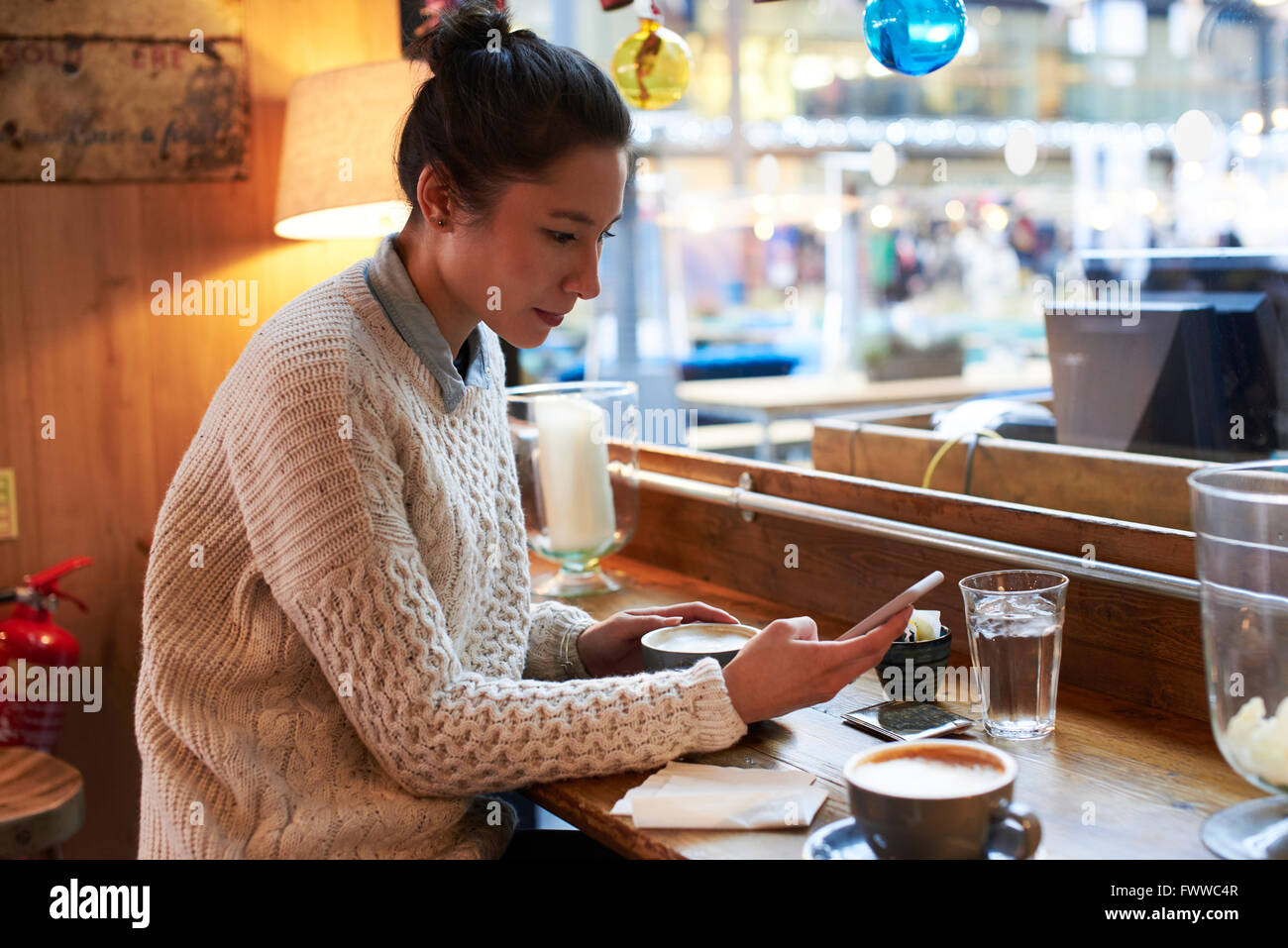 Junge Frau sitzt im Café lesen SMS Stockfoto