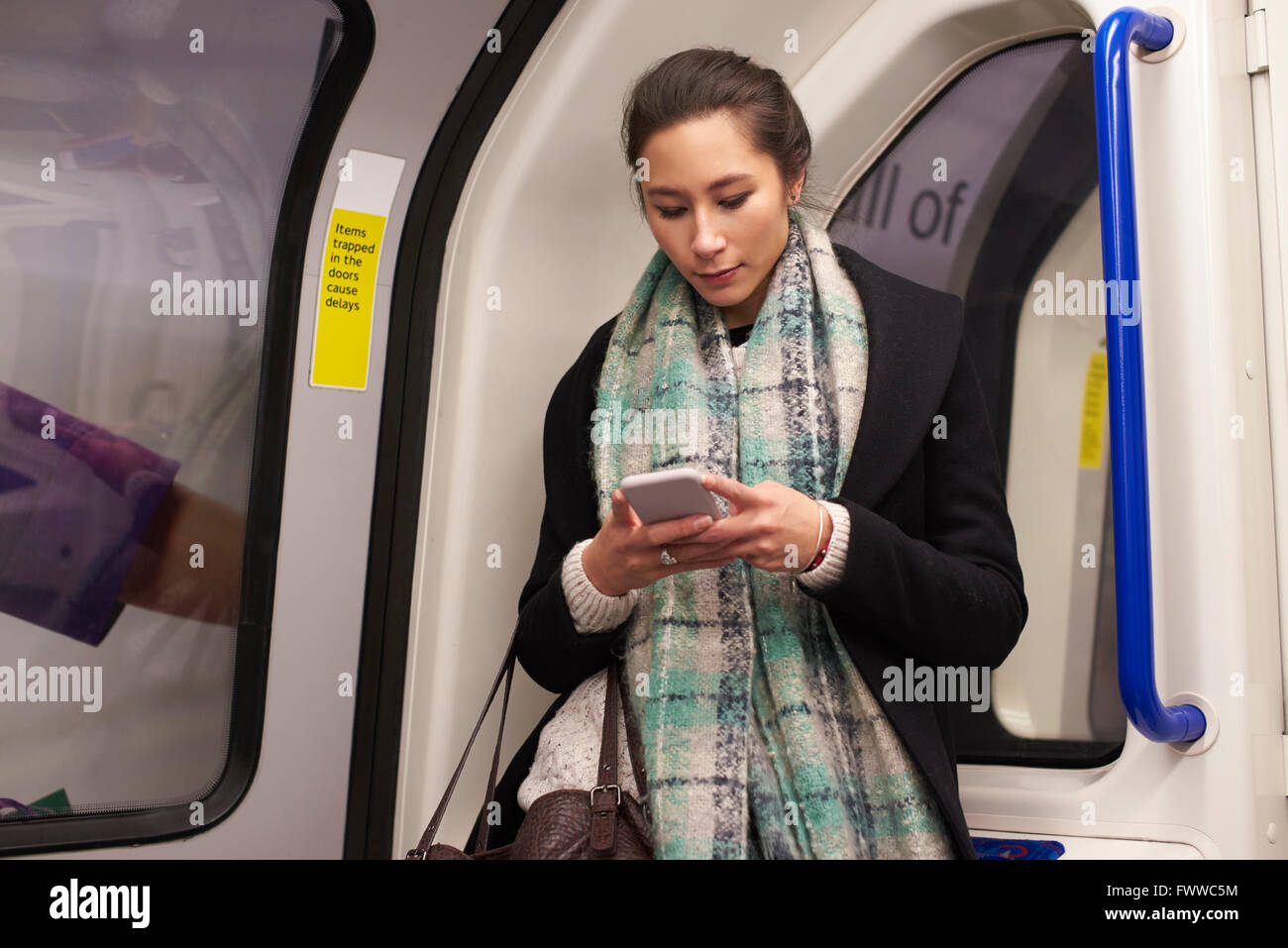Frau im U-Bahn Wagen Blick auf SMS Stockfoto