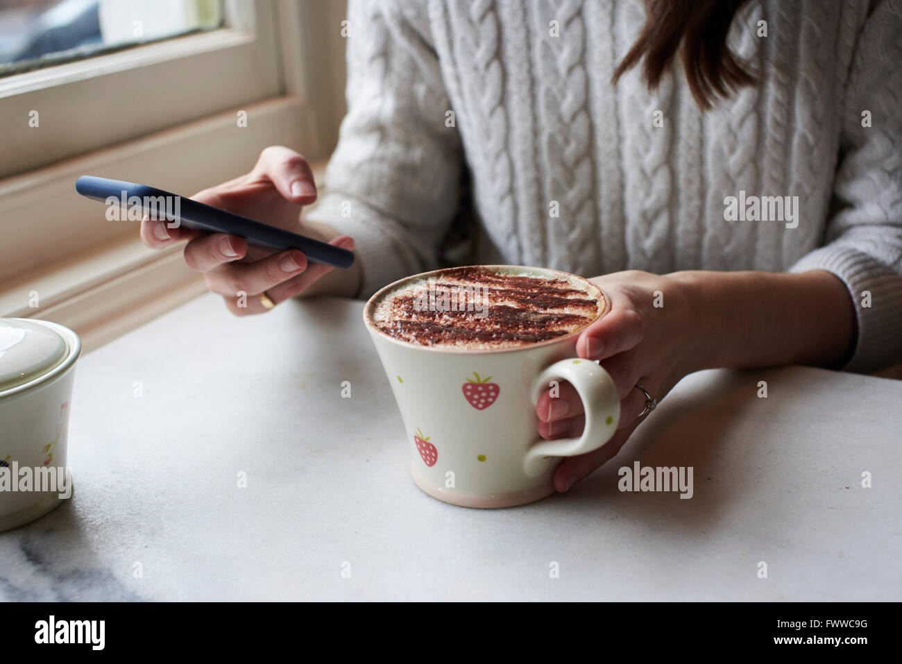 Frau, SMS und trinken Cappuccino Stockfoto