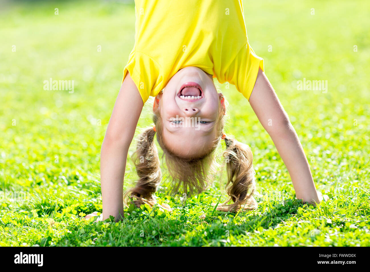 junge Mädchen stehen auf dem Kopf stehend auf dem Kopf auf dem Rasen im Sommer Stockfoto