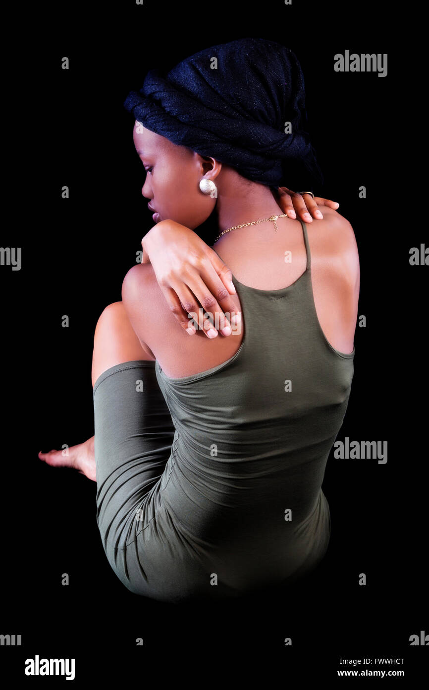 Schwarze Frau sitzt mit dem Rücken zum Betrachter grünes Kleid Stockfoto