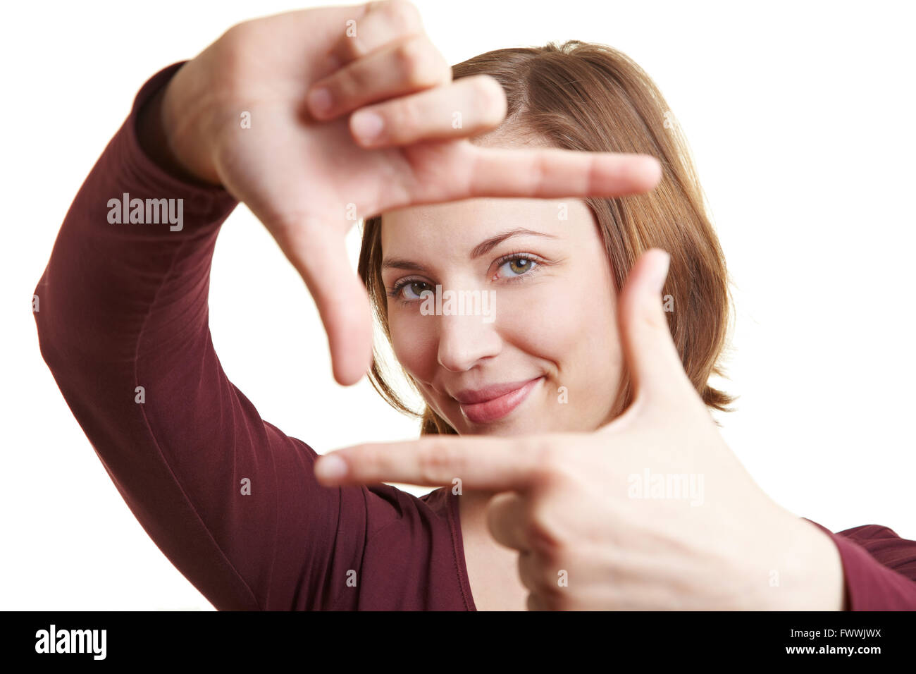 Frau hält ihre Finger als Rahmen vor ihr Gesicht und Durchsicht Stockfoto