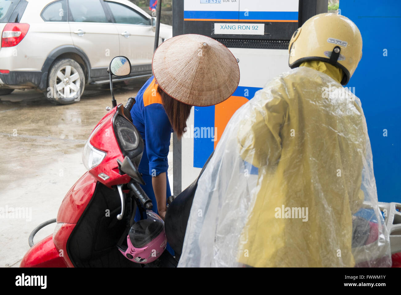 Benzin weibliche Tankwart füllt sich ein Kunden-Roller an einer Tankstelle in Sapa, Vietnam, Asien Stockfoto