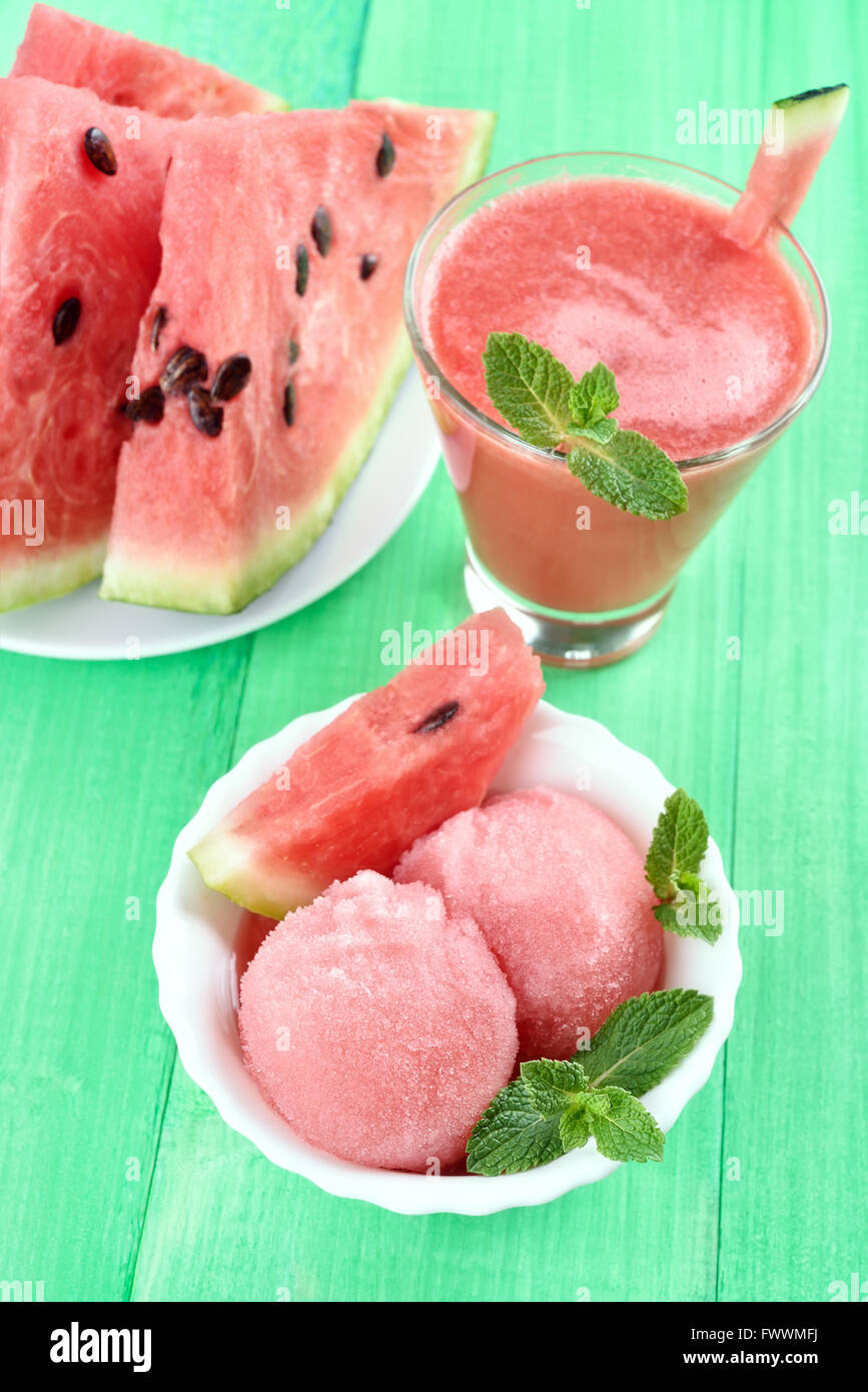 Wassermelone Eis, Smoothies und Scheiben auf grünem Hintergrund aus Holz Stockfoto