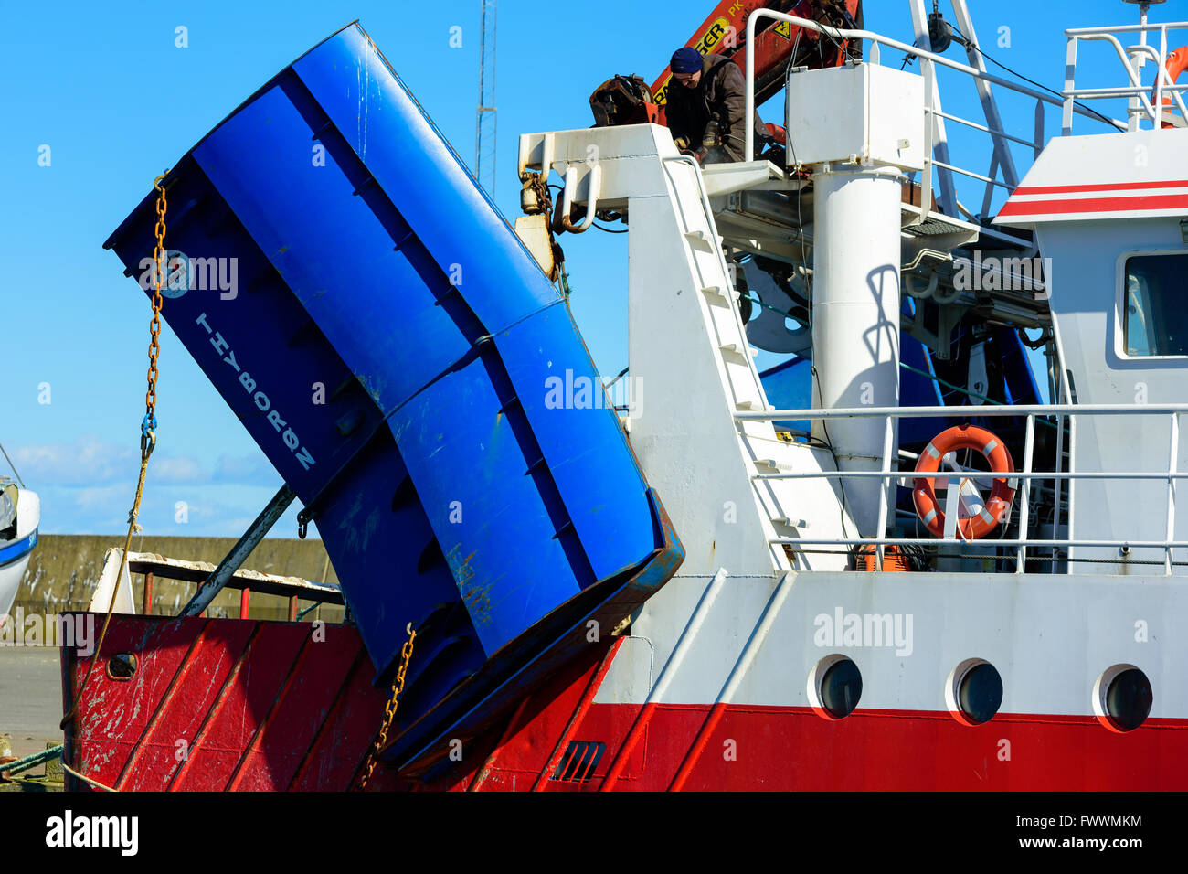 Simrishamn, Schweden - 1. April 2016: Männliche Arbeiter sitzen auf einer Brücke auf einem Trawler Fischerboot mit einem Winkelschleifer. Stockfoto