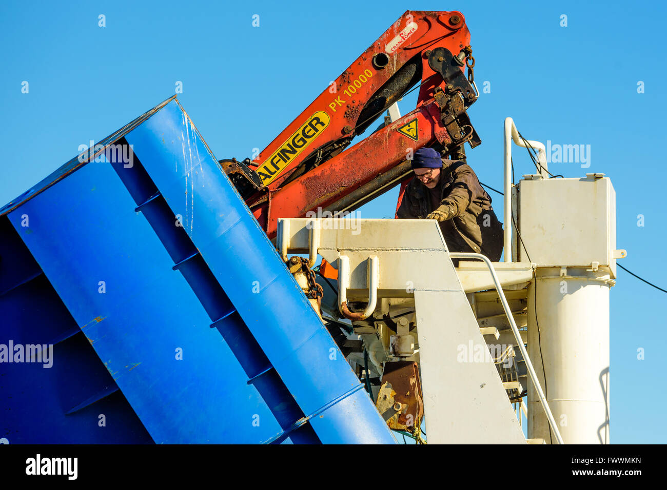 Simrishamn, Schweden - 1. April 2016: Männliche Arbeiter sitzen auf einer Brücke auf einem Trawler Fischerboot mit einem Winkelschleifer. Stockfoto