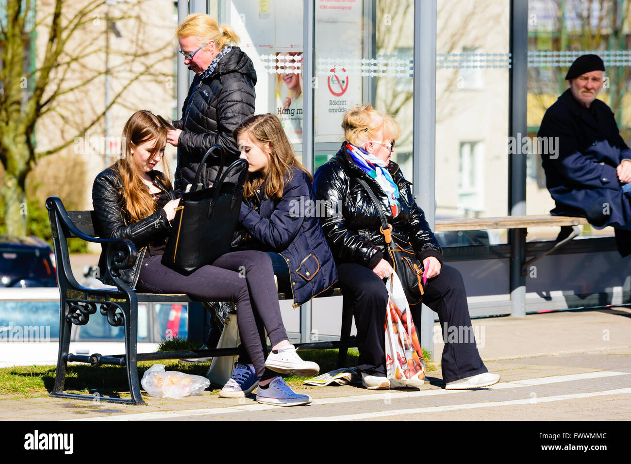 Simrishamn, Schweden - 1. April 2016: Menschen warten auf einen Bus außerhalb einer Wartehalle. Echte Menschen im Alltag. Stockfoto