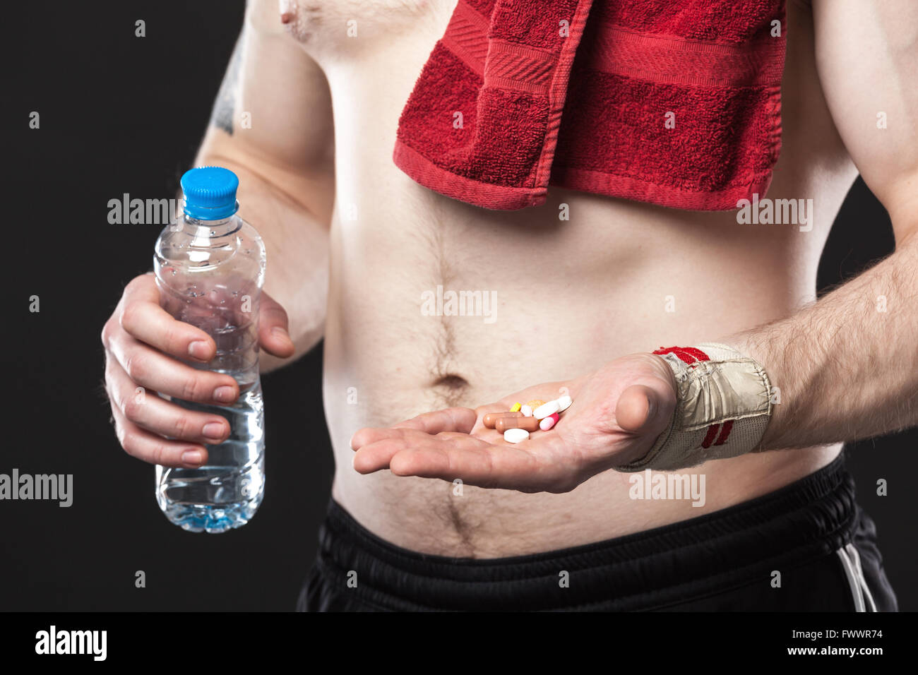 Junger Mann hält eine andere farbige Pillen auf schwarzem Hintergrund Stockfoto