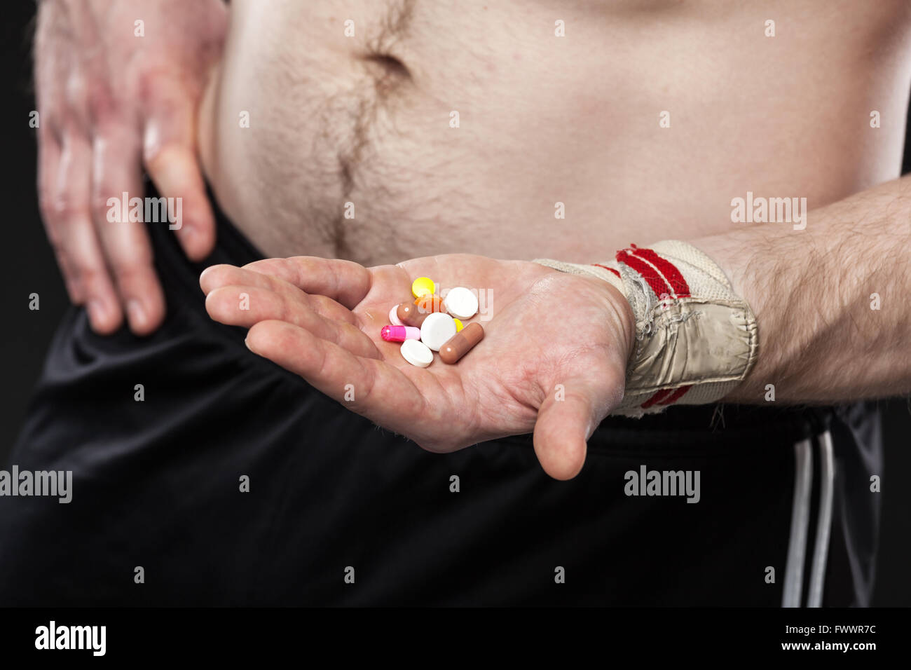 Junger Mann hält eine andere farbige Pillen auf schwarzem Hintergrund Stockfoto