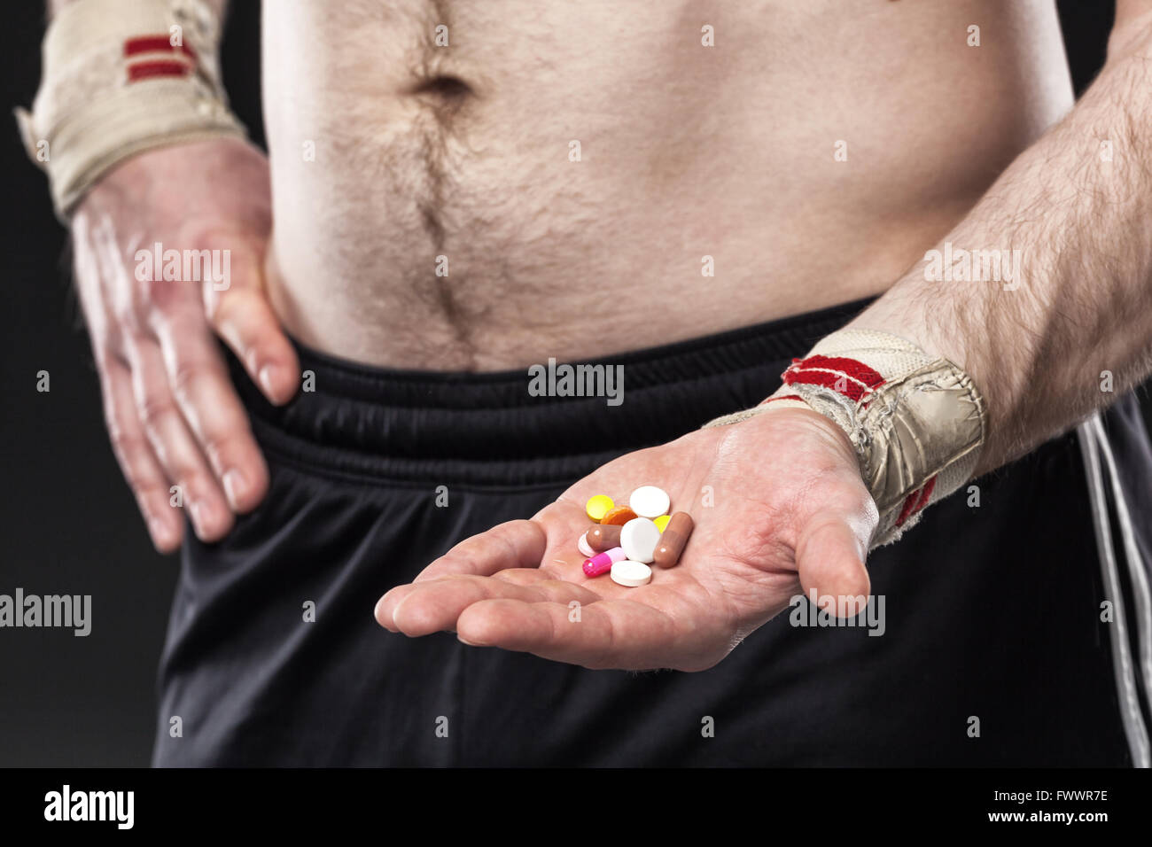 Junger Mann hält eine andere farbige Pillen auf schwarzem Hintergrund Stockfoto