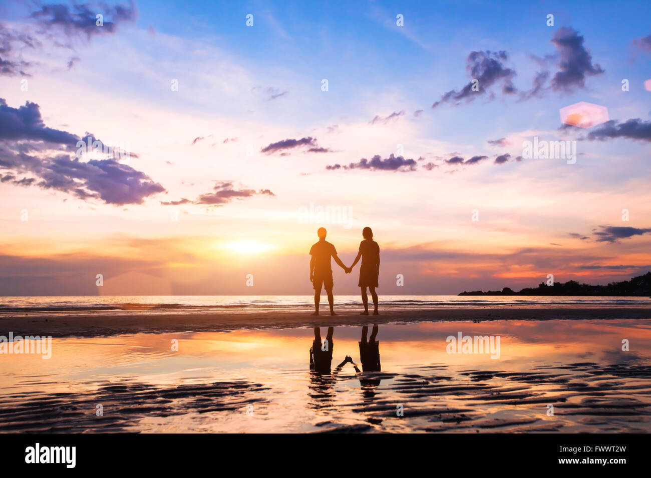 romantisch zu zweit am Strand bei Sonnenuntergang, Silhouetten von Mann und Frau zusammen Stockfoto