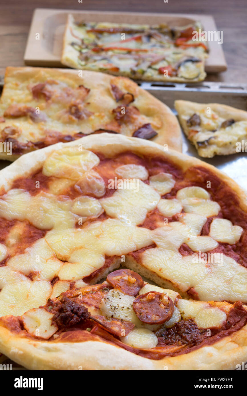 Runde Pizza mit Salami und Mozzarella und andere Stücke der hausgemachte Pizza Stockfoto