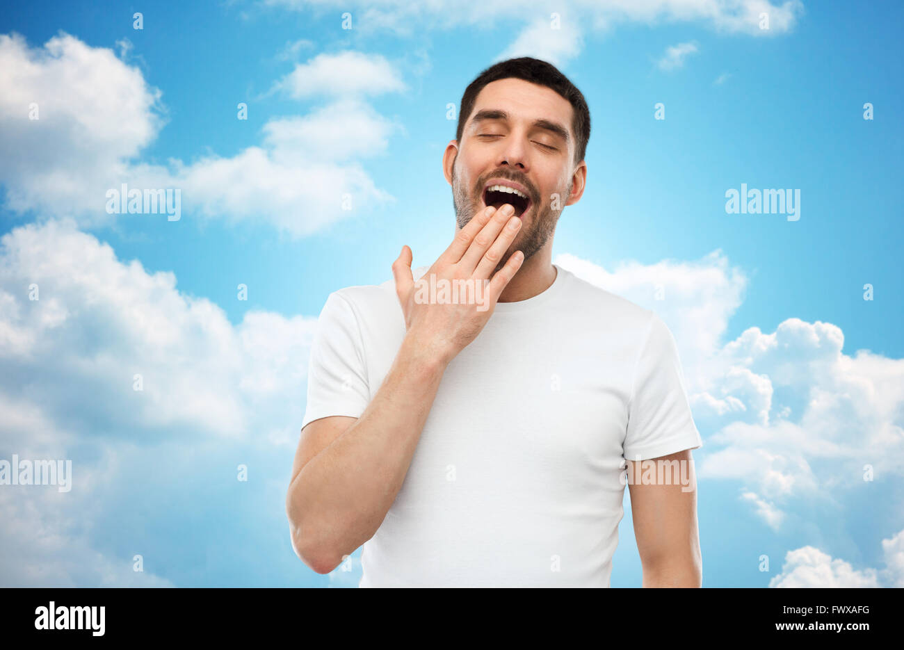 gähnende Mann über blauen Himmelshintergrund Stockfoto